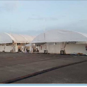 multiple large white dome-shaped tents in a row, empty industrial lot, dusk lighting, wide shot