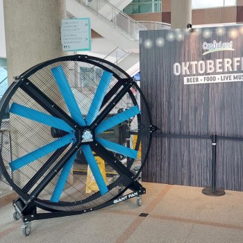 large industrial standing fan in mall lobby near Oktoberfest event signage backdrop with string lights