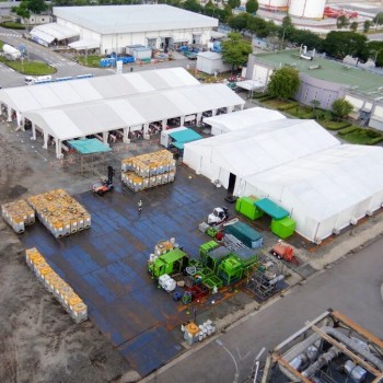 aerial view of industrial warehouse complex, multiple large white and grey buildings, roads and parking areas