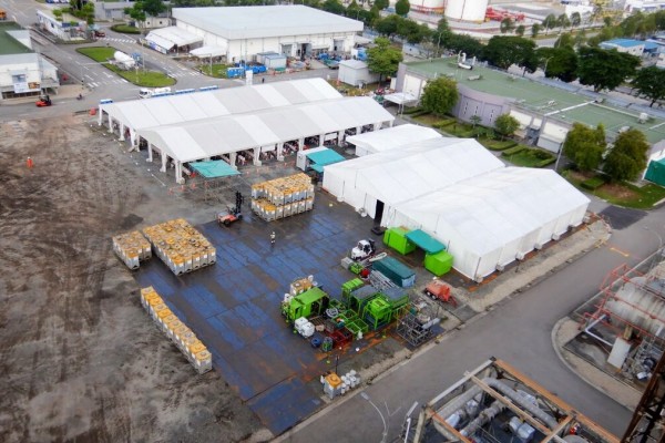aerial view of industrial warehouse complex, multiple large white and grey buildings, roads and parking areas