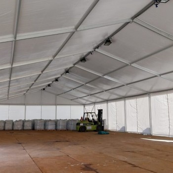 interior of white industrial storage tent, forklift and stacked pallets on one side, wooden floor covering