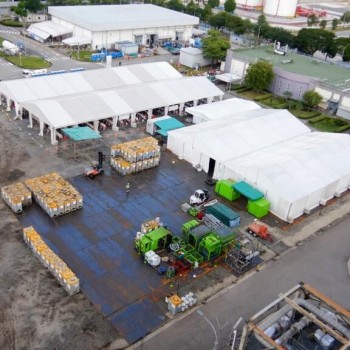aerial drone view of large white event tents at industrial logistics site, forklifts and generators nearby
