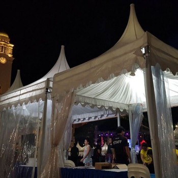 white pagoda tent with clear PVC sides at night event near historic clock tower building, staff and crowd nearby