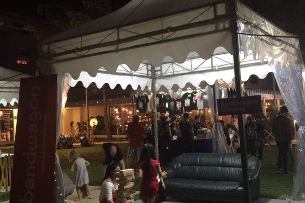 white pagoda tent at night garden festival event, people playing lawn game, sofa nearby, festive evening event