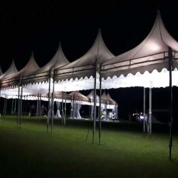 row of white pagoda tents lit up at night on grass field, empty, dark night sky