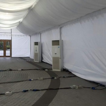 interior of empty white draped tent with two large portable aircon units against the wall, wooden double door entrance