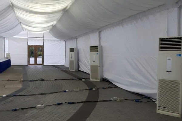 interior of empty white draped tent with two large portable aircon units against the wall, wooden double door entrance