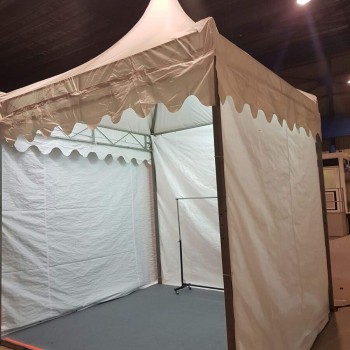 interior of empty white pagoda tent set up indoors in warehouse, single light bulb, dark background