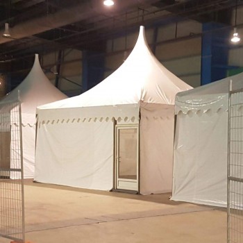 white pagoda tent set up indoors in warehouse fenced construction area, empty, no people