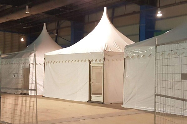white pagoda tent set up indoors in warehouse fenced construction area, empty, no people