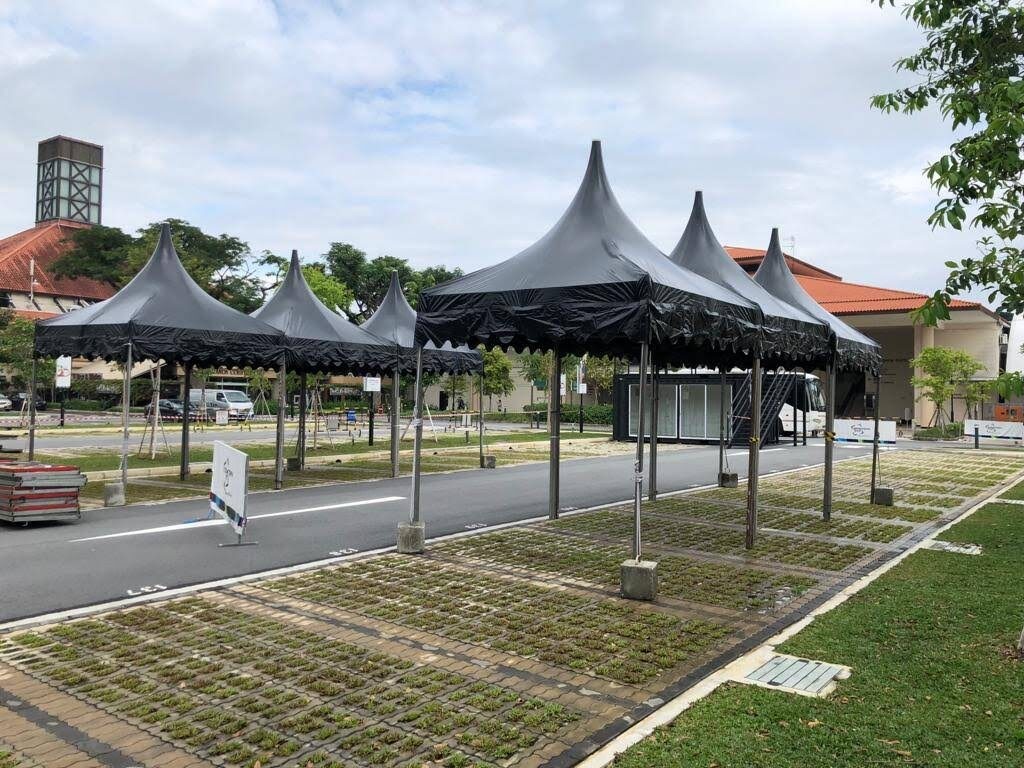 black pagoda tents in a row on paved outdoor path, residential estate setting, empty, daytime