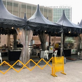 grey pagoda-style tents outdoor plaza near Mandarin Oriental hotel, yellow barrier fencing, empty setup before event