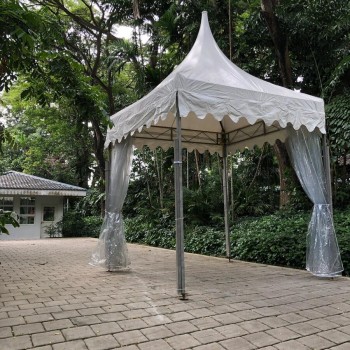white pagoda tent in leafy garden near white cottage building, empty, daytime