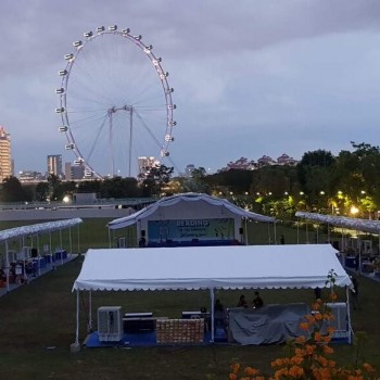outdoor evening event with white tents in park, Singapore Flyer visible in background, dusk lighting