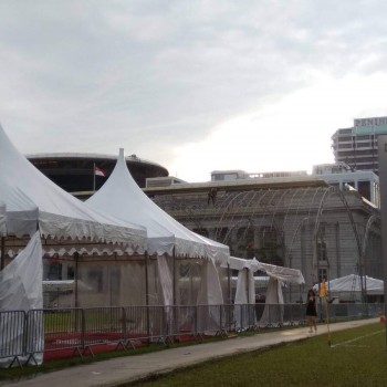 white A-frame tent along building with domed roof, barrier fencing, person standing, overcast daytime