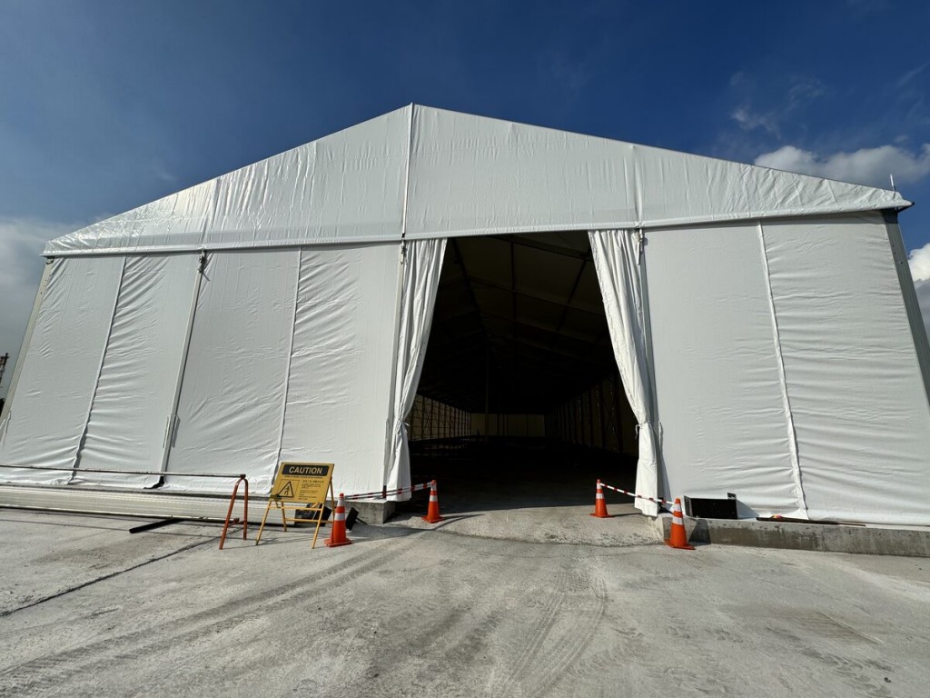 outdoor daytime white A-frame tent, open front entrance, traffic cones outside, empty, no people
