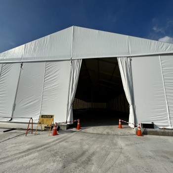outdoor daytime white A-frame tent, open front entrance, traffic cones outside, empty, no people