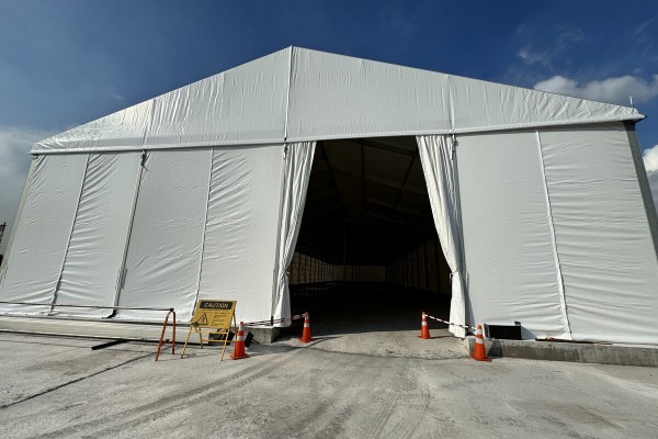 outdoor daytime white A-frame tent, open front entrance, traffic cones outside, empty, no people