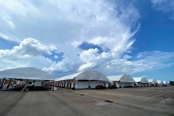 outdoor row of dome-shaped tents seen from a distance, empty lot, dramatic cloudy sky, daytime, no people