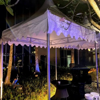 white draped tent with purple mood lighting, outdoor garden setting at night, rattan furniture, empty