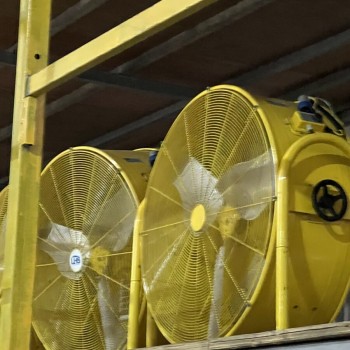 close-up of large yellow industrial ventilation fans stored in warehouse, no people