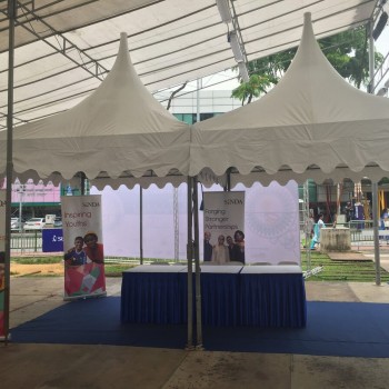 beige pagoda tents at outdoor street community outreach event, blue-skirted table with informational banner stands
