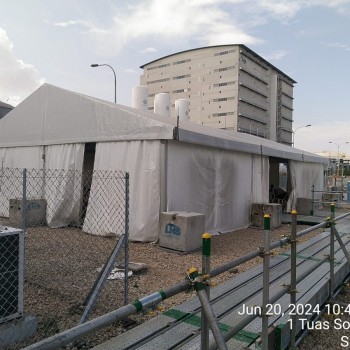 white tent at fenced industrial worksite, Tuas South Lane Singapore, tank building in background, daytime, timestamped photo