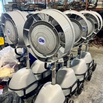 row of large industrial misting cooling fans on wheels, indoor warehouse storage, company logo visible on fan