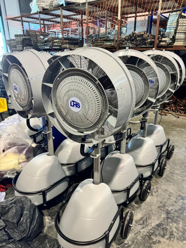 row of large industrial misting cooling fans on wheels, indoor warehouse storage, company logo visible on fan